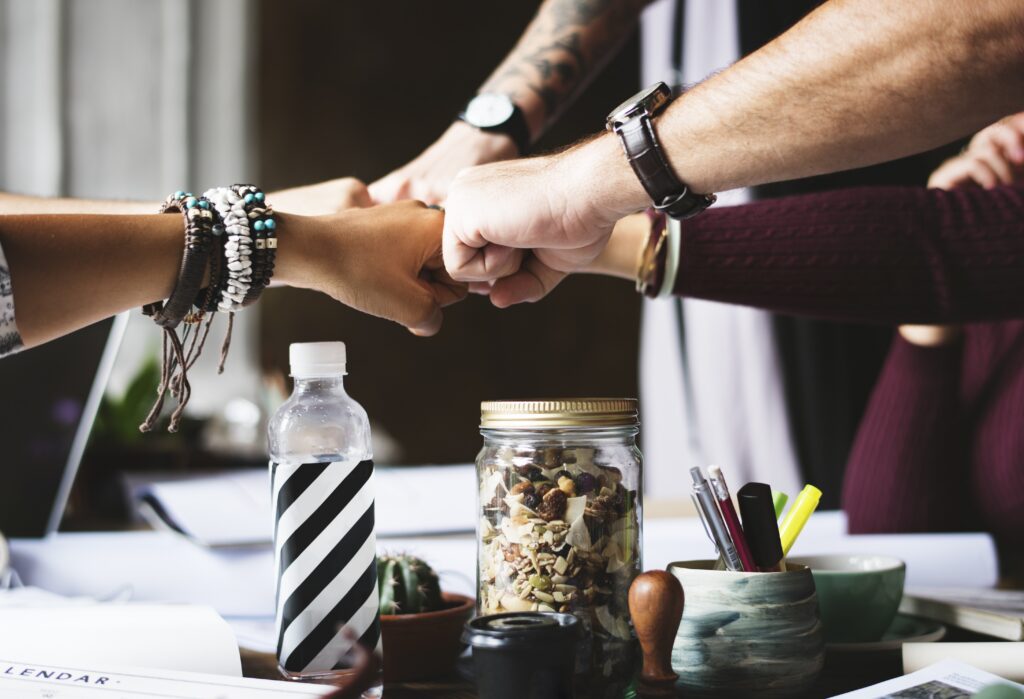 Diverse office team fist bump over desk symbolizing teamwork and employee collaboration